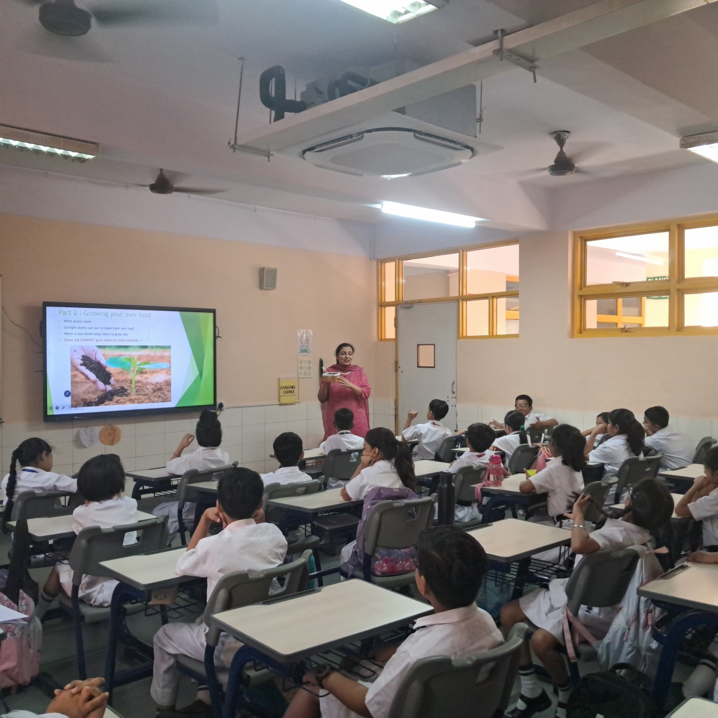 Class 3 students in white uniforms listening to the Soil Therapy session