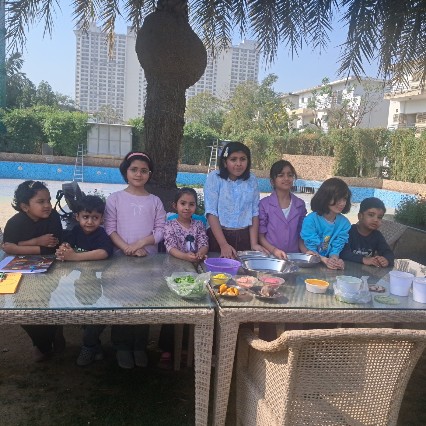 Group of children posing behind the Holi colour-making table