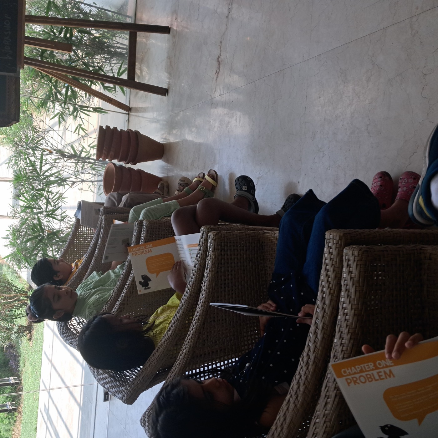 Children reading compost workshop booklets titled Chapter One Problem