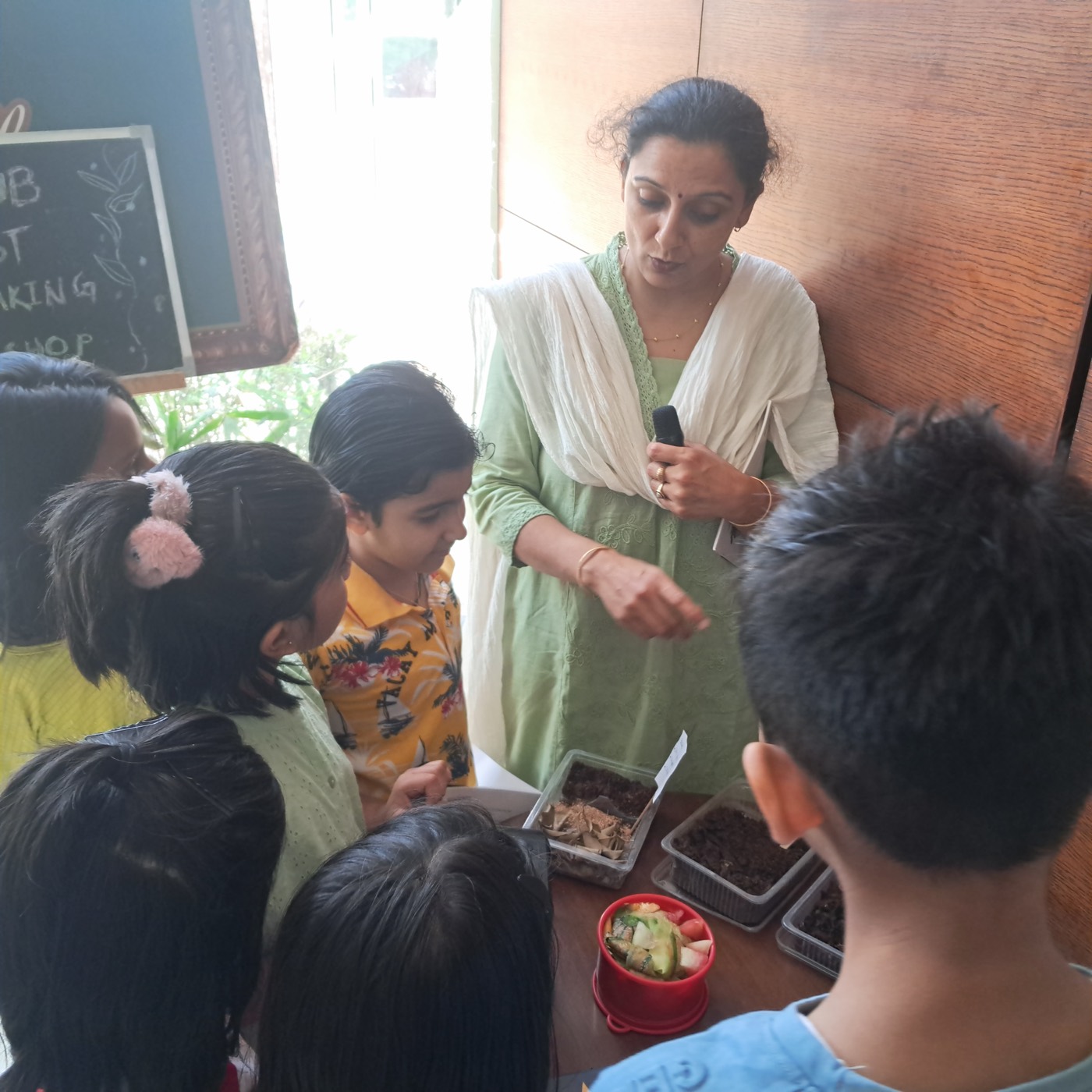 Facilitator showing children compost samples and fruit scraps